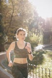 Healthy fitness athletic woman jogging outdoors. Attractive brunette female runner running in city park airpods stock photography Healthy fitness athletic woman jogging outdoors. Attractive brunette female runner running in city park airpods stock photography