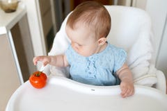 Healthy food for children. Adorable little baby sitting in her chair and playing with vegetables . small girl eat tomato royalty free stock photo Healthy food for children. Adorable little baby sitting in her chair and playing with vegetables . small girl eat tomato royalty free stock photo