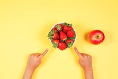 Healthy food concept. Kids hands finger pointing to bowl with fresh strawberries on yellow background royalty free stock photos Healthy food concept. Kids hands finger pointing to bowl with fresh strawberries on yellow background royalty free stock photos