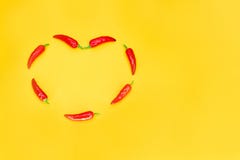 Heart shaped red chili peppers on yellow background with copy space. Passionate love concept stock photo Heart shaped red chili peppers on yellow background with copy space. Passionate love concept stock photo