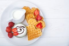 Heart shaped waffles with strawberries, cream sauce, pitcher with milk on white plate and white background. stock image Heart shaped waffles with strawberries, cream sauce, pitcher with milk on white plate and white background. stock image