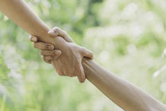 Helping hands concept. Hand holding for help on nature background