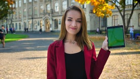 Hembra atractiva joven, estudiante que hojea en la tableta y que muestra la pantalla a la cámara, pulgares para arriba, sonriendo almacen de metraje de vídeo Hembra atractiva joven, estudiante que hojea en la tableta y que muestra la pantalla a la cámara, pulgares para arriba, sonriendo almacen de metraje de vídeo