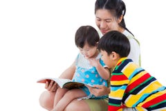 Hembra joven con dos pequeños niños asiáticos que leen un libro imágenes de archivo libres de regalías Hembra joven con dos pequeños niños asiáticos que leen un libro imágenes de archivo libres de regalías