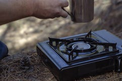 Herbal Tea In A Metal Mug In Hand Over A Portable Gas Stove Royalty Free Stock Photography Herbal Tea In A Metal Mug In Hand Over A Portable Gas Stove Royalty Free Stock Photography