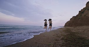 Hermosas Vistas Al Paisaje De La Playa Dos Atractivas SeÃ±oras Corriendo  Juntas Por La MaÃ±ana Usando La Ropa Deportiva Metrajes - Vídeo de  corriendo, deportiva: 157644560