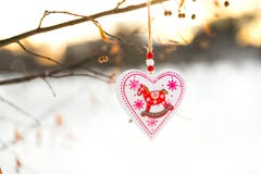 Herz formte das Valentinsgruß- oder Weihnachtsdekorationsspielzeug, das am Baumast mit Schnee auf dem Hintergrund hängt Stockfotos Herz formte das Valentinsgruß- oder Weihnachtsdekorationsspielzeug, das am Baumast mit Schnee auf dem Hintergrund hängt Stockfotos