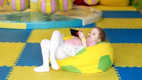 Het babymeisje bekijkt de mobiele telefoon Het kind speelt op smartphone stock video Het babymeisje bekijkt de mobiele telefoon Het kind speelt op smartphone stock video