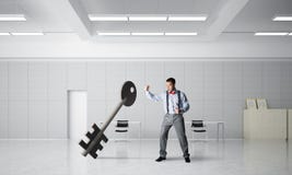 Het breken door toegangsconcept met de woedende mens die concrete sleutel verpletteren Stock Fotografie Het breken door toegangsconcept met de woedende mens die concrete sleutel verpletteren Stock Fotografie