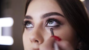 Het close-up van grimeurhand met het klein borstelwerk door het lagere ooglid, maakt rokerige oogmake-up Mooi stock footage Het close-up van grimeurhand met het klein borstelwerk door het lagere ooglid, maakt rokerige oogmake-up Mooi stock footage