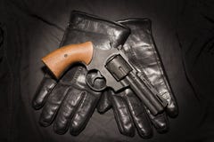 Het concept van de misdaad Zwart kanon met leerhandschoenen op donkere doek stock afbeelding Het concept van de misdaad Zwart kanon met leerhandschoenen op donkere doek stock afbeelding