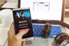 Het de holdingsscherm van de mensenhand van Apple-muziek app wordt geschoten die op Andro tonen die stock afbeelding Het de holdingsscherm van de mensenhand van Apple-muziek app wordt geschoten die op Andro tonen die stock afbeelding