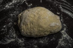 Het deeg voor baksel ligt op een lijst in bloem royalty-vrije stock afbeelding Het deeg voor baksel ligt op een lijst in bloem royalty-vrije stock afbeelding