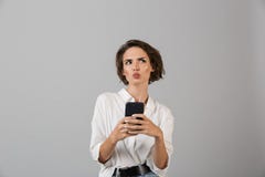 Het denken verwarde het jonge bedrijfsvrouw stellen geïsoleerd over grijze muurachtergrond gebruikend het mobiele telefoon babbel royalty-vrije stock fotografie Het denken verwarde het jonge bedrijfsvrouw stellen geïsoleerd over grijze muurachtergrond gebruikend het mobiele telefoon babbel royalty-vrije stock fotografie