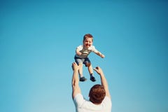 Het gelukkige blije kind, vaderpret werpt op zoon in de lucht, de zomer