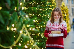 Het gelukkige jonge meisje in vakantiesweater met stapel van Kerstmis stelt voor stock afbeelding Het gelukkige jonge meisje in vakantiesweater met stapel van Kerstmis stelt voor stock afbeelding