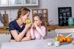 Het gelukkige meisje en haar mooie jonge moeder hebben samen ontbijt in een witte keuken Zij hebben pret en eten appelen royalty-vrije stock afbeeldingen Het gelukkige meisje en haar mooie jonge moeder hebben samen ontbijt in een witte keuken Zij hebben pret en eten appelen royalty-vrije stock afbeeldingen
