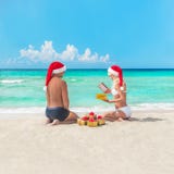 Het gelukkige paar bij strand in santahoeden het maken stelt voor christma voor Stock Afbeeldingen