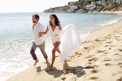 Het gelukkige romantische paar houdt hun handen en gaat op het strand in Griekenland, de wittebroodswekenvakantie, zonnige dag in stock foto's Het gelukkige romantische paar houdt hun handen en gaat op het strand in Griekenland, de wittebroodswekenvakantie, zonnige dag in stock foto's