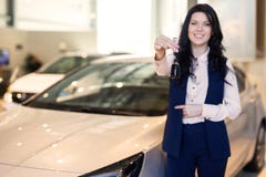 Het gelukkige vrouwenkoper possing met sleutels dichtbij haar nieuw voertuig in het autohandel drijven royalty-vrije stock afbeelding Het gelukkige vrouwenkoper possing met sleutels dichtbij haar nieuw voertuig in het autohandel drijven royalty-vrije stock afbeelding