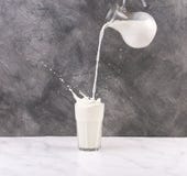 Het gieten van een glas melk die tot plons leidt royalty-vrije stock fotografie Het gieten van een glas melk die tot plons leidt royalty-vrije stock fotografie