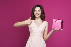 Het glimlachen brunette in een kleding die een giftdoos in haar handen houden stock afbeeldingen Het glimlachen brunette in een kleding die een giftdoos in haar handen houden stock afbeeldingen