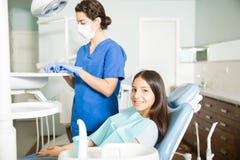 Het glimlachen Meisjeszitting op Stoel terwijl Tandarts Working In Clinic royalty-vrije stock afbeeldingen Het glimlachen Meisjeszitting op Stoel terwijl Tandarts Working In Clinic royalty-vrije stock afbeeldingen