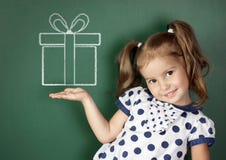 Het glimlachen van getrokken de giftdoos van het kindmeisje greep dichtbij schoolbord royalty-vrije stock afbeelding Het glimlachen van getrokken de giftdoos van het kindmeisje greep dichtbij schoolbord royalty-vrije stock afbeelding