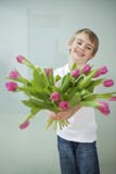 Het glimlachen van jongen het standhouden tulpenbloemen tegen grijze achtergrond Royalty-vrije Stock Foto's Het glimlachen van jongen het standhouden tulpenbloemen tegen grijze achtergrond Royalty-vrije Stock Foto's