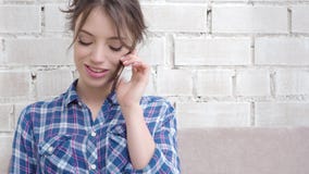 Het glimlachen vrouwenzitting op bank in de woonkamer die een telefoongesprek hebben stock footage Het glimlachen vrouwenzitting op bank in de woonkamer die een telefoongesprek hebben stock footage