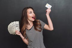 Het glimlachende jonge geld van de dameholding en debetkaart in handen Stock Afbeelding Het glimlachende jonge geld van de dameholding en debetkaart in handen Stock Afbeelding