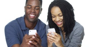 Het jonge Afrikaanse Amerikaanse paar texting op cel telefoneert samen stock fotografie Het jonge Afrikaanse Amerikaanse paar texting op cel telefoneert samen stock fotografie