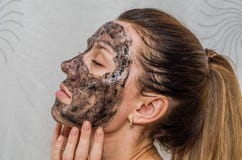 Het jonge charmante meisje maakt een zwart houtskoolmasker op haar gezicht Royalty-vrije Stock Foto Het jonge charmante meisje maakt een zwart houtskoolmasker op haar gezicht Royalty-vrije Stock Foto
