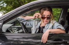 Het jonge charmante meisje in zonnebril zit bij het wiel van een auto Royalty-vrije Stock Foto Het jonge charmante meisje in zonnebril zit bij het wiel van een auto Royalty-vrije Stock Foto