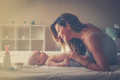 Het jonge moeder spelen met haar babyjongen in bed Moeder die van I genieten stock fotografie Het jonge moeder spelen met haar babyjongen in bed Moeder die van I genieten stock fotografie