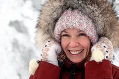 Het jonge mooie glimlachende meisje in roze gebreide hoed met pompon en de witte vuisthandschoenen met patroon in warm jasje van stock foto Het jonge mooie glimlachende meisje in roze gebreide hoed met pompon en de witte vuisthandschoenen met patroon in warm jasje van stock foto