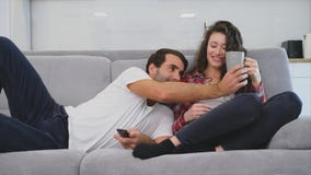 Het jonge paar ontspannen in hun flat, het liggen op de laag en het letten van de op film stock footage Het jonge paar ontspannen in hun flat, het liggen op de laag en het letten van de op film stock footage