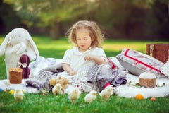 Het kind zit op een weide rond Pasen-decoratie stock foto Het kind zit op een weide rond Pasen-decoratie stock foto