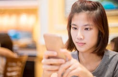 Het leuke Aziatische meisje gebruikt een mobiele telefoon in koffie Royalty-vrije Stock Foto's Het leuke Aziatische meisje gebruikt een mobiele telefoon in koffie Royalty-vrije Stock Foto's