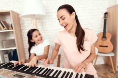 Het mamma en het meisje spelen thuis de synthesizer Zij rusten en hebben pret stock foto's Het mamma en het meisje spelen thuis de synthesizer Zij rusten en hebben pret stock foto's
