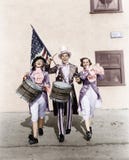 Het marcheren band die in een parade met een Amerikaanse vlag presteren (Alle afgeschilderde personen leven niet langer en geen l royalty-vrije stock afbeelding Het marcheren band die in een parade met een Amerikaanse vlag presteren (Alle afgeschilderde personen leven niet langer en geen l royalty-vrije stock afbeelding