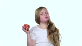 Het meisje bijt een appel en toont duimen Witte achtergrond Langzame Motie stock video Het meisje bijt een appel en toont duimen Witte achtergrond Langzame Motie stock video
