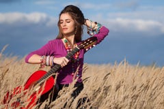 Het meisje die van het land haar haar bevestigen en een akoestische gitaar op gebied houden tegen blauwe bewolkte hemelachtergron Royalty-vrije Stock Afbeelding Het meisje die van het land haar haar bevestigen en een akoestische gitaar op gebied houden tegen blauwe bewolkte hemelachtergron Royalty-vrije Stock Afbeelding