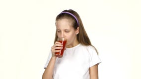 Het meisje drinkt tomatesap en bewondert het en toont de klasse Witte achtergrond stock footage Het meisje drinkt tomatesap en bewondert het en toont de klasse Witte achtergrond stock footage