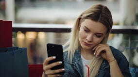 Het mooie blondemeisje neemt selfie op haar telefoonzitting in koffie met het winkelen zakken stock video Het mooie blondemeisje neemt selfie op haar telefoonzitting in koffie met het winkelen zakken stock video