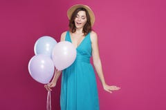 Het mooie brunette in een blauwe kleding en strohoed houdt ballons stock afbeeldingen Het mooie brunette in een blauwe kleding en strohoed houdt ballons stock afbeeldingen