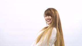 Het mooie glimlachende meisje met lang haar toont duimen bij witte achtergrond stock footage Het mooie glimlachende meisje met lang haar toont duimen bij witte achtergrond stock footage