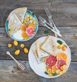 Het ontbijtreeks van de de lentevitamine Dun omfloerst of pannekoeken met verse grapefruit, sinaasappel, kumquat, honings, room e royalty-vrije stock fotografie Het ontbijtreeks van de de lentevitamine Dun omfloerst of pannekoeken met verse grapefruit, sinaasappel, kumquat, honings, room e royalty-vrije stock fotografie
