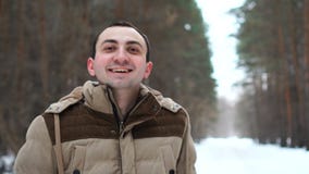 Het portret van de jonge mens in jasje lacht met gelukkig gezicht Mensentribunes in de winterbos stock video Het portret van de jonge mens in jasje lacht met gelukkig gezicht Mensentribunes in de winterbos stock video