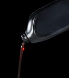 Het rode het smeermiddel van de motorolie gieten van zwarte plastic fles Royalty-vrije Stock Foto Het rode het smeermiddel van de motorolie gieten van zwarte plastic fles Royalty-vrije Stock Foto